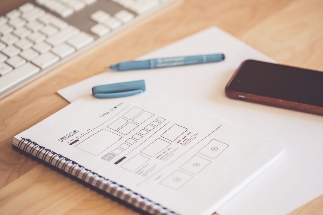 Adana kurumsal web sitesi kurulumu rehberi için masa üzerinde wireframe çizimi bulunan not defteri ve telefon
